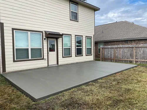 Concrete patio in backyard of house.